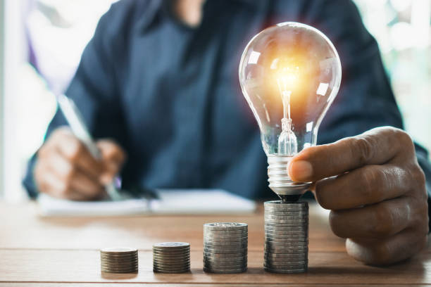 istock Business man holding light bulb on the desk in office and writing on note book it for financial,accounting,energy,idea concept. 1158227551