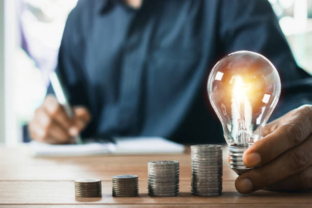 istock Business man holding light bulb on the desk in office and writing on note book it for financial,accounting,energy,idea concept. 1158227559