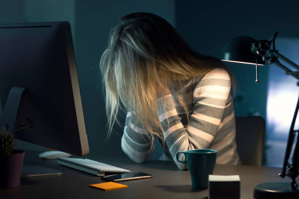夜遅くデスクで働く疲れた女性 - furniture internet adult blond hair ストックフォトと画像