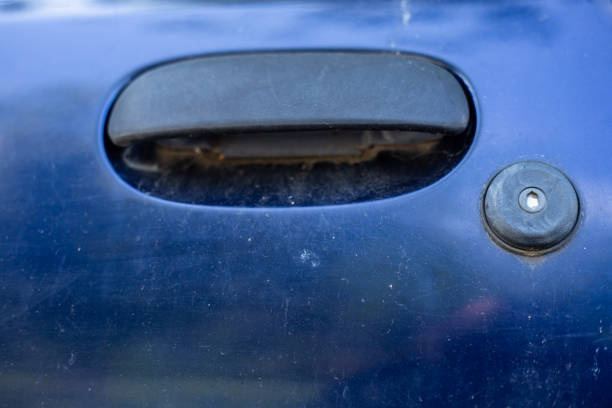 Close-up shot of a car handle and key lock Black plastic handle and metallic silver lock of modern car with dark color – Closed dusty door of auto vehicle with round keylock for protection door lever stock pictures, royalty-free photos & images