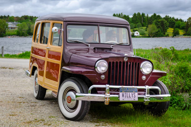 Chester, Nova Scotia, Canada - June 22, 2019 : 1950 Willys Jeep Woodie Station Wagon at annual Graves Island Car Show at Graves Island Provincial Park, Chester, Nova Scotia, Canada. Three people sit inside the classic Jeep.
