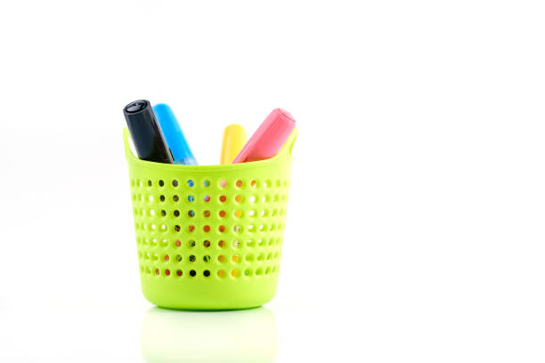 Green plastic basket  with colorful pen isolated on white background