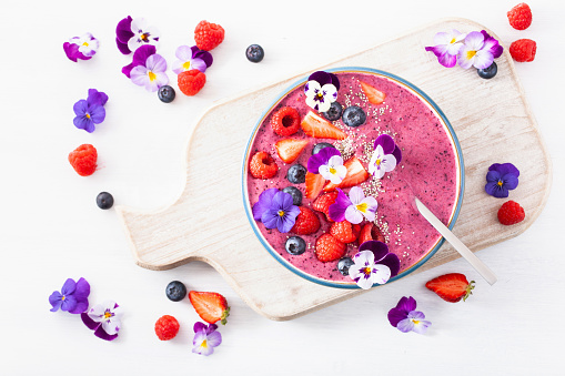 healthy summer berry smoothie bowl with flowers and chia seed