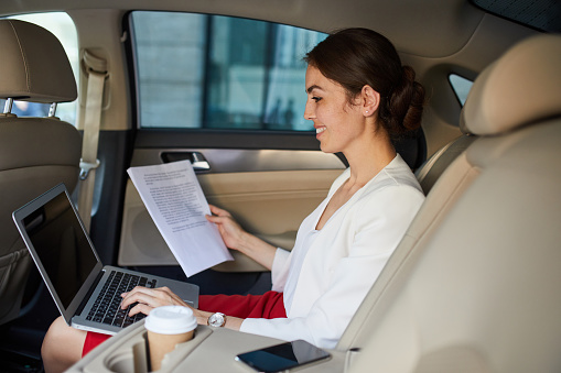 Side view portrait of successful businesswoman working in car, copy space