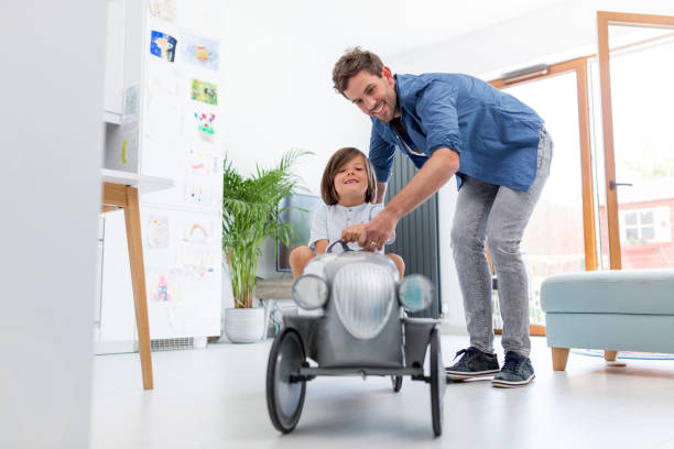 istock Father helping his son to drive a toy peddle car 1158237538