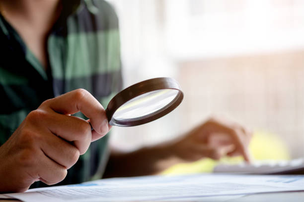 istock Businessman looking through a magnifying glass to documents. Business assessment and audit. Magnifying glass on a financial report. Close-up Of Businessperson Checking Bills With Magnifying Glass.Concept of search. 1158238927