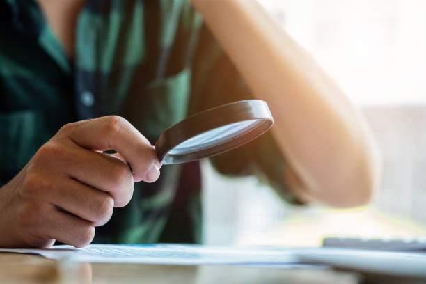 istock Businessman looking through a magnifying glass to documents. Business assessment and audit. Magnifying glass on a financial report. Close-up Of Businessperson Checking Bills With Magnifying Glass.Concept of search. 1158238965
