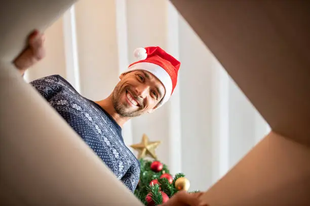 Photo of Young man unpacking christmas present