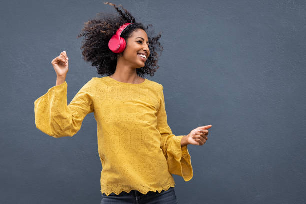 african woman dancing and listening music - young adult technology beautiful singing imagens e fotografias de stock