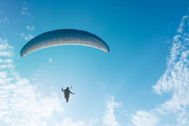 парашютист парит в красивом голубом небе со светлыми облаками - airplane sky extreme sports men стоковые фото и изображения