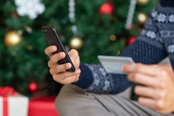 istock Man hand holding phone and card on christmas 1158243303