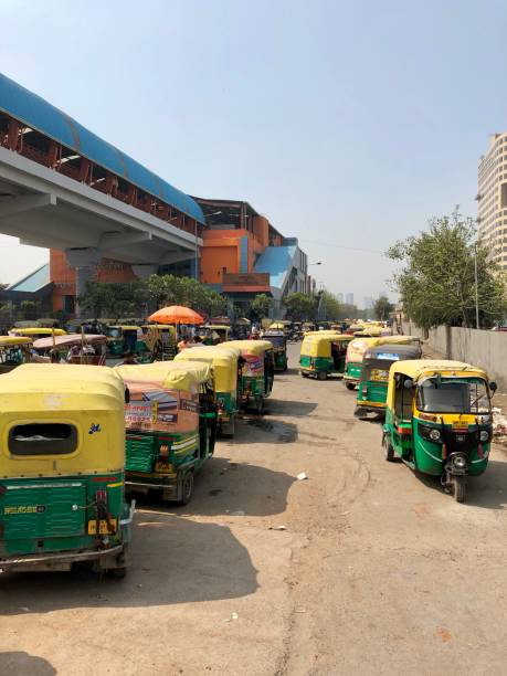 Image of Indian auto rickshaws taxi cab rank, yellow and green tuk tuks transport photo, parked in a row Wave Noida City Centre, Delhi Metro, Sector 32, Noida, India Wave Noida City Centre, Sector 32, Noida, India - March 18, 2019: Auto rickshaws parked in a row awaiting passenger fares at Wave Noida City Centre, a station on the Blue Line of the Delhi Metro, New Delhi, India. delhi metro stock pictures, royalty-free photos & images