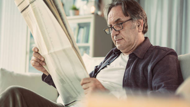 istock Senior man reading newspaper at home 1158244571