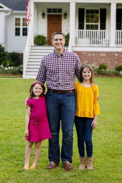 istock dad and two daughters outside their home 1158244657