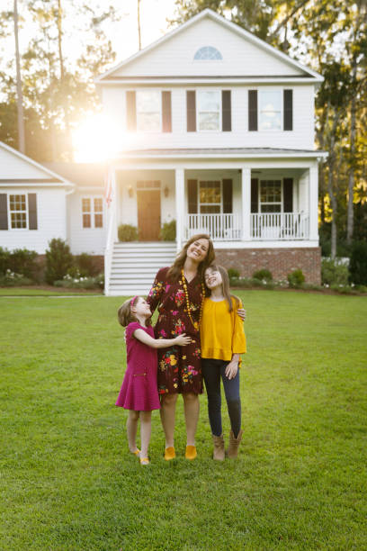istock mom and two daughters outside their home 1158244740