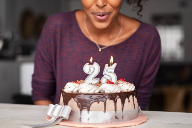 ケーキの上に誕生日のキャンドルを吹くアフリカの女性 - cake birthday candle blowing ストックフォトと画像