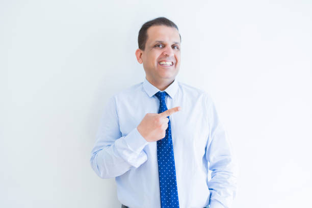 istock Middle age business man smiling and pointing to the side over white background 1158245097