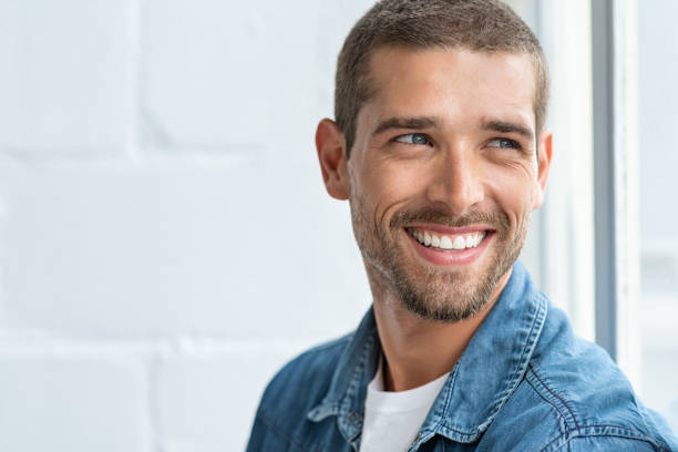 Happy smiling man looking away Confident young man looking away with big smile. Happy handsome guy looking through window thinking about the future. Closeup face of smiling casual man imagine with copy space. teeth photos stock pictures, royalty-free photos & images