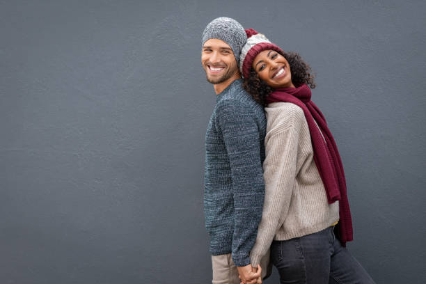 pareja feliz con ropa de invierno apoyada contra la espalda - cardigan men african ethnicity african descent fotografías e imágenes de stock