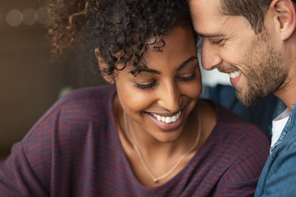 Romantic multiethnic couple in love Portrait of attractive couple embracing each other. Closeup loving multiethnic couple embracing and kissing. Closeup face of cheerful boyfriend and african girl cuddling in love at home. young couple stock pictures, royalty-free photos & images