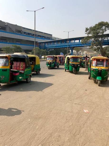 Image of Indian auto rickshaws taxi cab rank, yellow and green tuk tuks transport photo, parked in a row Sector 52 Metro Station, Delhi Metro, Noida, India Sector 52 Metro Station, Noida, India - March 18, 2019: Auto rickshaws parked in a row awaiting passenger fares at Sector 52 Metro Station, a station on the Blue Line of the Delhi Metro, New Delhi, India. delhi metro stock pictures, royalty-free photos & images