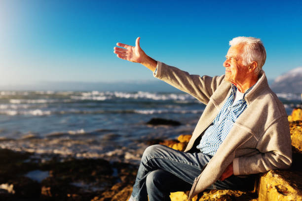 istock Handsome senior man gestures expansively beside the ocean 1158248034