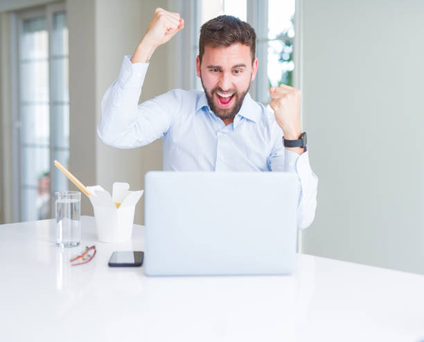 istock Business man eating take away asian noodles food while working using computer laptop and smiling 1158248423