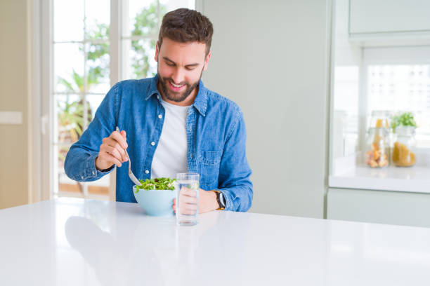 istock Handsome man eating green peas at home 1158248519