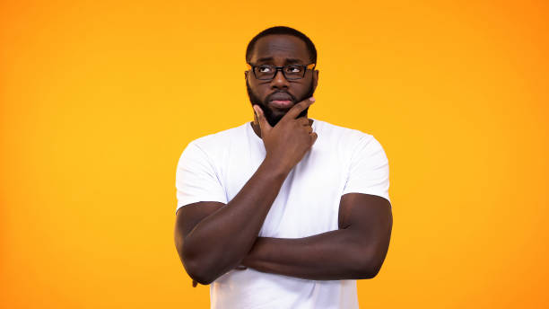 istock Smart young black student in glasses thinking about answer, yellow background 1158248865