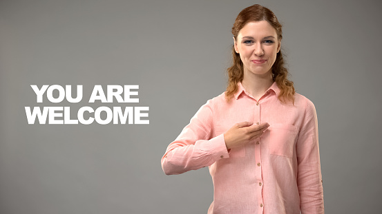 Deaf female saying you are welcome in asl, text on background, interpreter