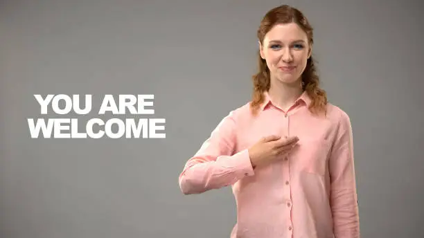 Deaf female saying you are welcome in asl, text on background, interpreter