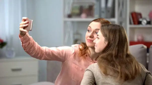 Two young woman taking selfie by smartphone, female friends leisure, technology