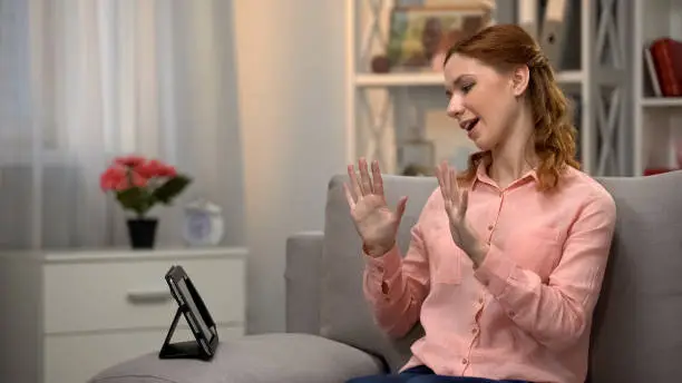 Lady communicating by asl gestures with friend via tablet, language for deaf