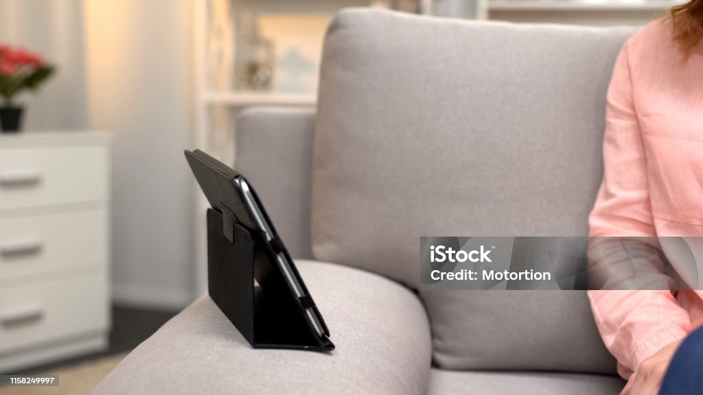 Tablet in case on sofa front of woman, gadget communication, modern technology Digital Tablet Stock Photo