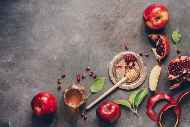 Photo of Apples, pomegranate and honey on a dark rustic background. Traditional Jewish food. New Year - Rosh Hashanah. Top view, copy space, flat lay.