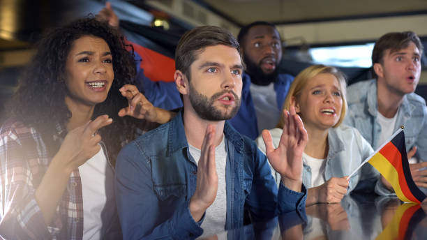 istock Nervous supporters waving German flag, watching sports program in bar, hope 1158250133
