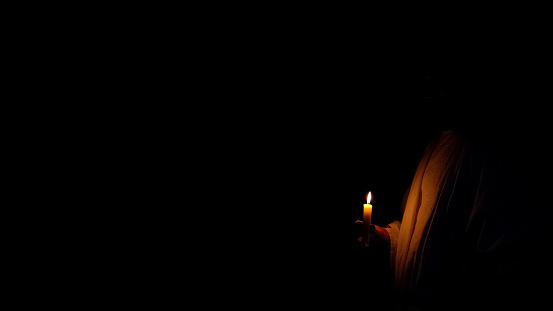 Person holding candle in darkness, prayer and memory of victims, template