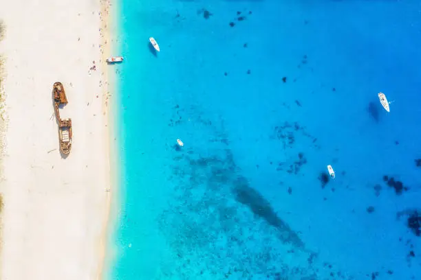 Aerial top down view to the Navagio shipwreck beach on Zakynthos island, Greece, with people having fun in the blue sea and fine sand