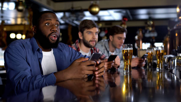 istock African-american man checking bets on smartphone, watching match in bar, app 1158250439