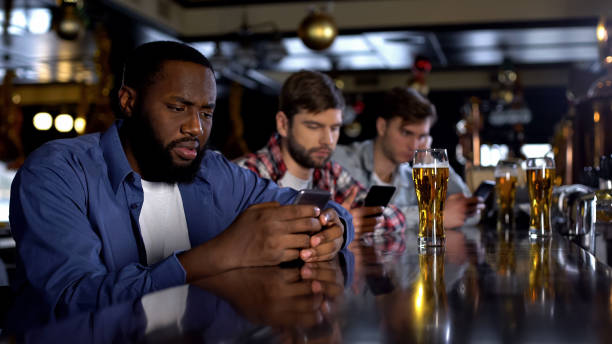 istock Bored men scrolling phones in pub replacing live communication, gadget addiction 1158250442