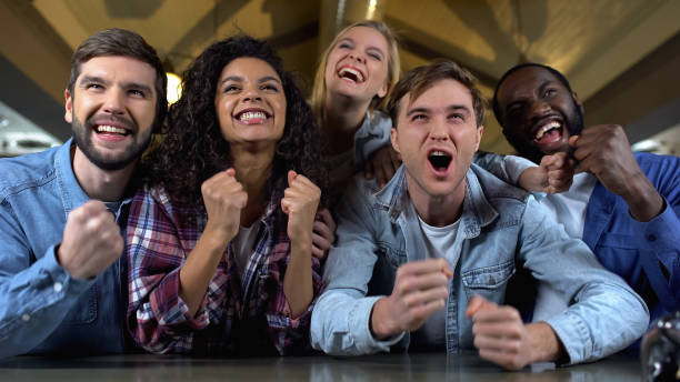istock Positive young people rooting for team goal, watching match together, audience 1158250679