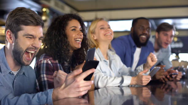 aficionados al deporte apostando en línea por la aplicación de teléfono inteligente durante el partido, celebrando el gol - match sport leisure games sport apps fotografías e imágenes de stock