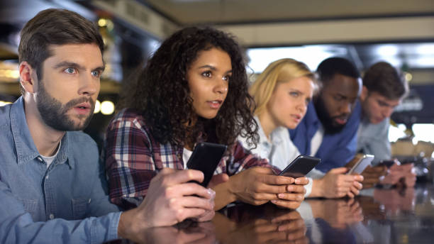 aficionados al deporte haciendo apuestas en línea por la aplicación de teléfono inteligente durante el partido, gol de espera - match sport leisure games sport apps fotografías e imágenes de stock