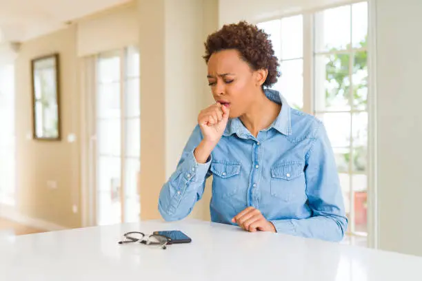 Photo of Young beautiful african american woman feeling unwell and coughing as symptom for cold or bronchitis. Healthcare concept.