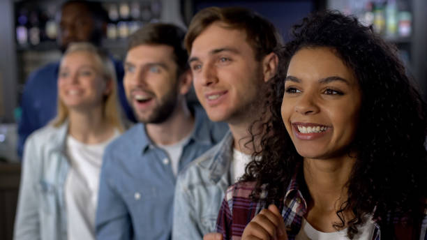 istock Smiling mixed-race friends rooting for team, watching contest, event audience 1158250963