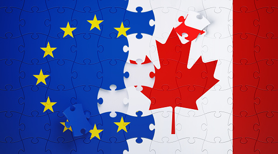 Jigsaw puzzle pieces textured with European Union and Canadian flags. Horizontal composition with copy space and selective focus. Solution concept.