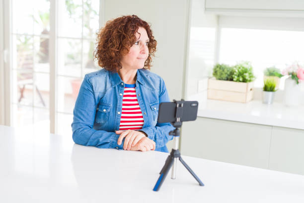 istock Senior woman doing video chat using smartphone camera looking to side, relax profile pose with natural face with confident smile. 1158253260