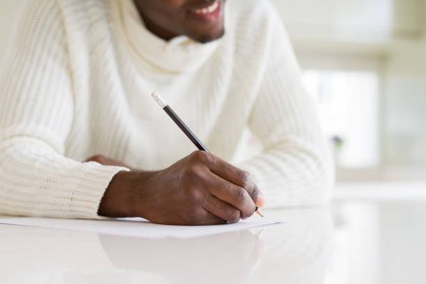istock Close up of african man writing a note on a paper smiling confident 1158253440