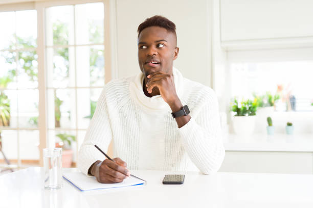 istock African american student man writing on a paper using a pencil serious face thinking about question, very confused idea 1158253447