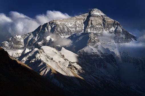 Dramatic evening light across the north face of Mount Everest in Himalayas of Tibet \nMount Everest, known in Nepali as Sagarmatha and in Tibetan as Chomolungma, is Earth's highest mountain above sea level, located in the Mahalangur Himal sub-range of the Himalayas. The international border between Nepal and China runs across its summit point